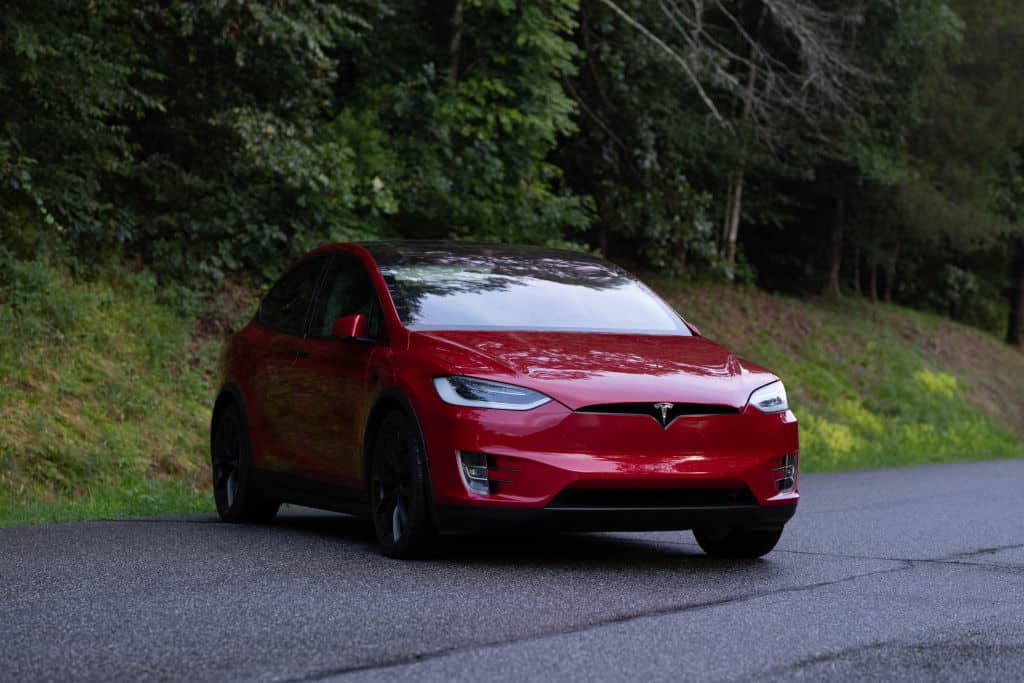 Red 2018 Tesla Model X in forest road